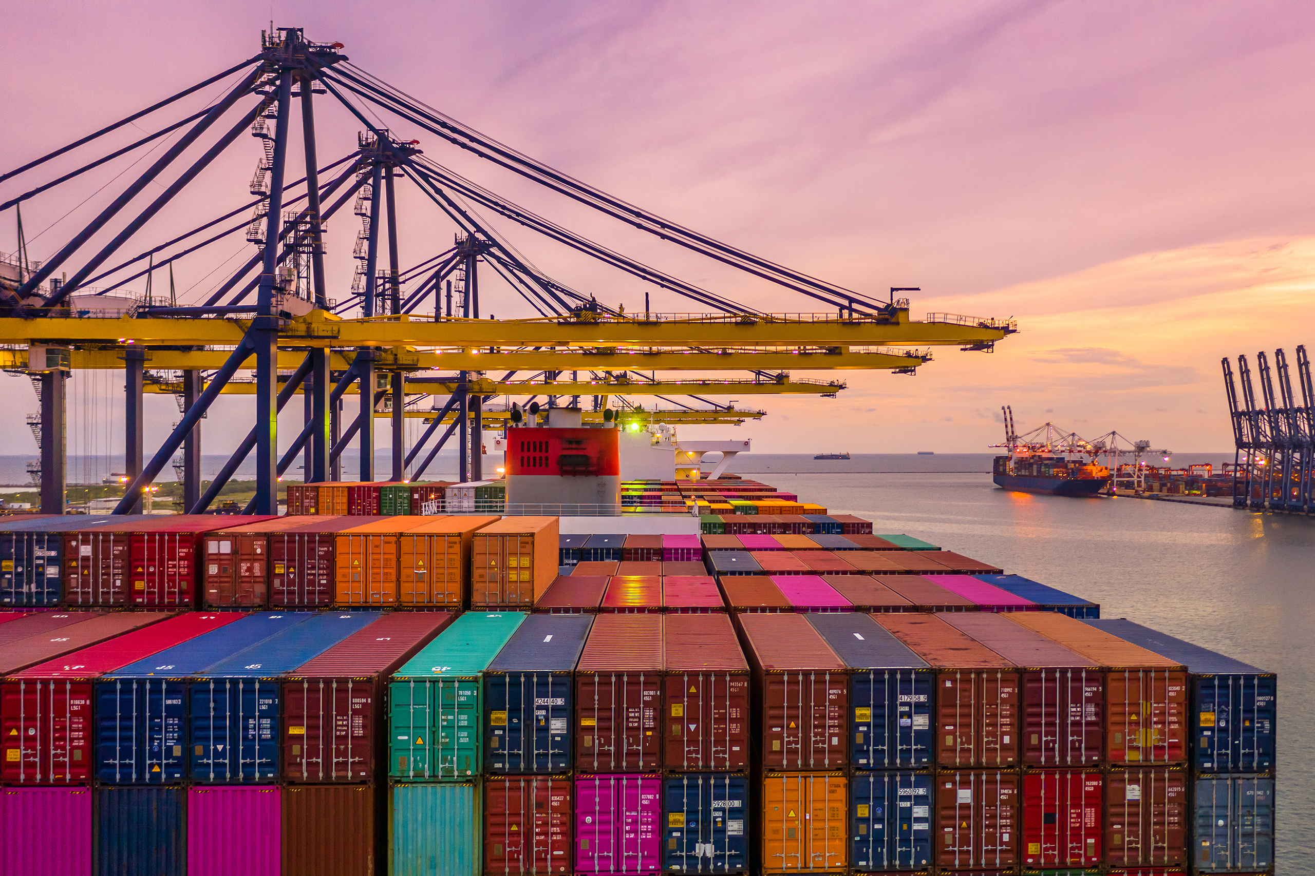 Container ship loading and unloading in deep sea port at sunset,